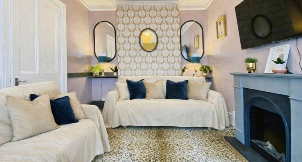 Bohemian lounge with upcycled furniture, open-style fireplace, and large TV at the Bournemouth Hot Tub Garden hen party house.