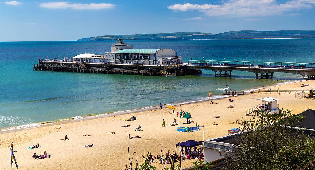 Sunny Bournemouth Pier extending into clear ocean waters from sandy beach, setting the stage for a Bournemouth stag do.