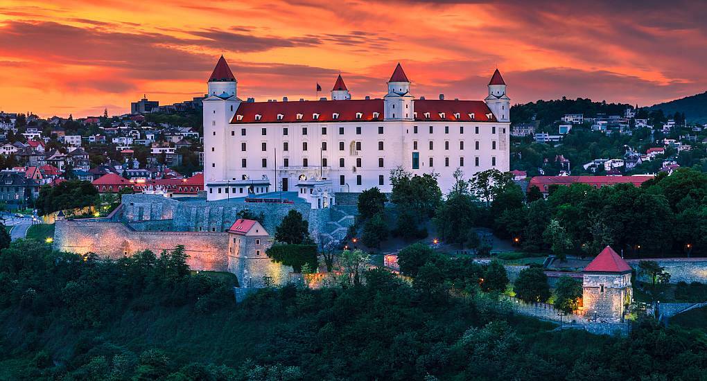 Bratislava Castle with red roofs illuminated at sunset on a hilltop, scenic backdrop for a Bratislava hen do.