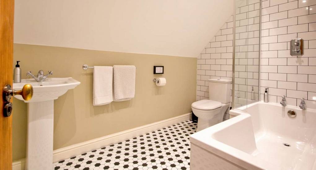Modern tiled bathroom with full bathtub at Godfrey Manor, a premium Derbyshire hen party stay in the Peak District.