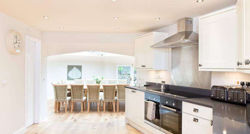 Modern kitchen looking through to the open plan dining area at Peak Star, a traditional Derbyshire stone hen party house.