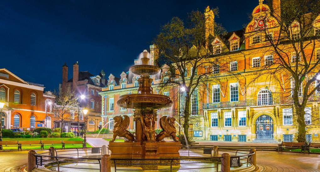 Illuminated fountain in Town Hall Square at night with Leicester Town Hall in the background for a Leicester hen do.