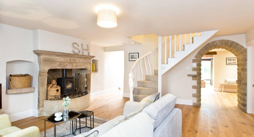 View through the original stone archway in Star House at Peak Star, showing the open-plan lounge and traditional fireplace.