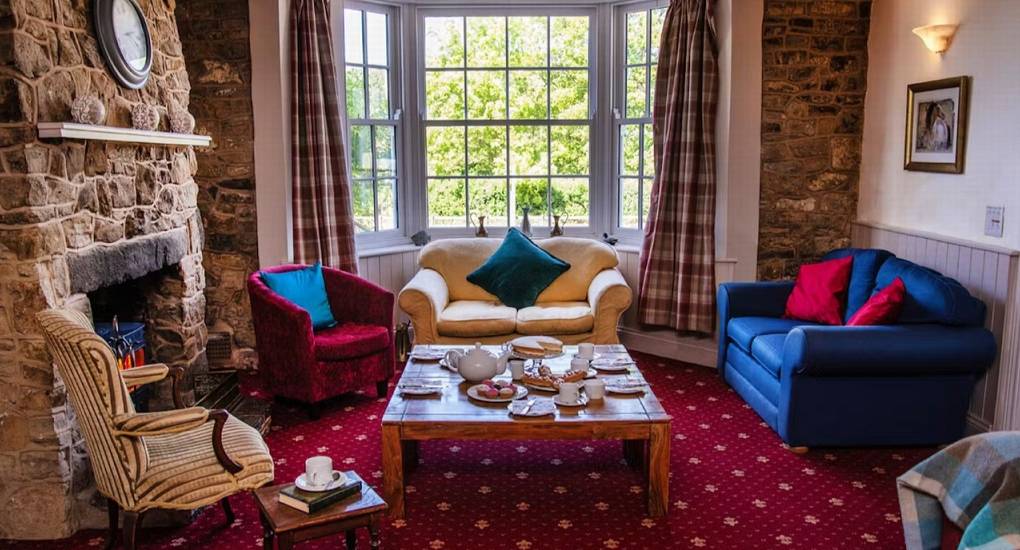 A view of one of the lounge areas at Ross Lodge Gloucestershire, featuring comfortable sofas and a large bay window, ideal for relaxing during your hen do accommodation stay.