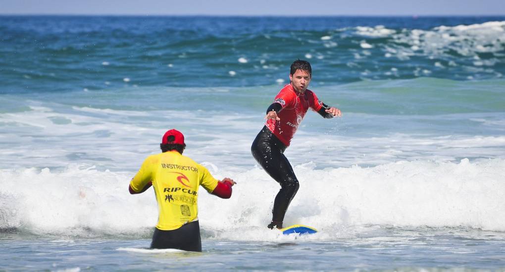 Stag learning to surf under the watchful eye of an instructor